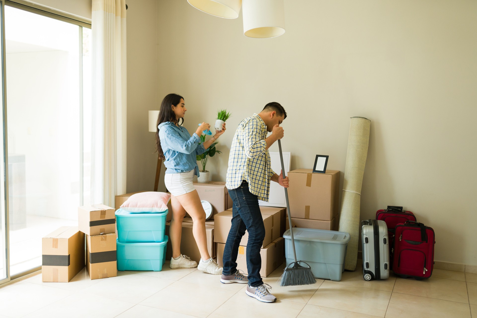 Young couple cleaning the new house after moving boxes