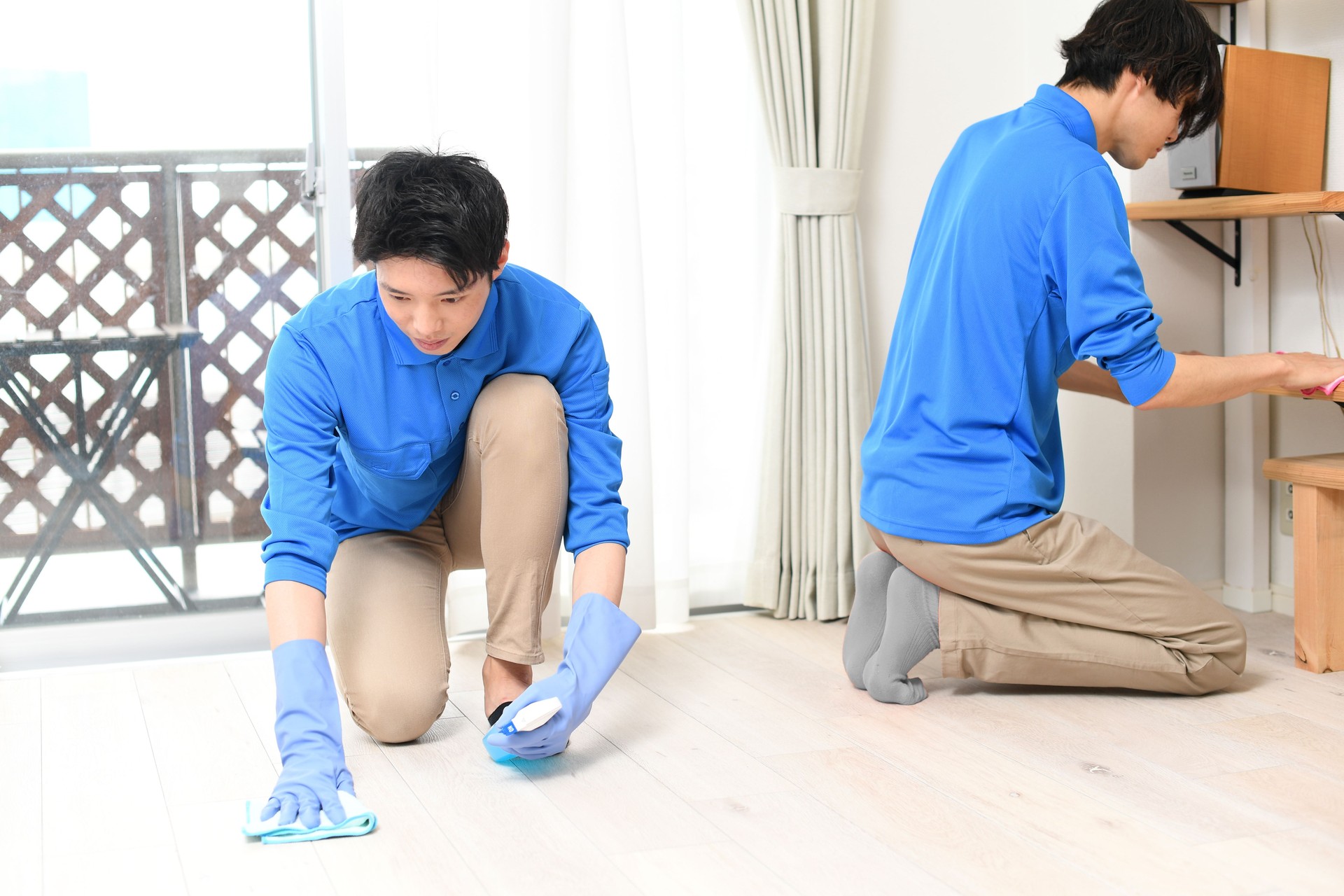 Several young Asian men who work for a house cleaning company are cleaning the floors of a house.